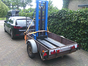 Vier robuuste spanbanden (op deze foto twee zichtbaar) worden gratis meegeleverd en moeten gebruikt worden. Onze aanhanger -die te huur is- heeft een lage tildrempel, en een hoog rek voor het vastzetten. 