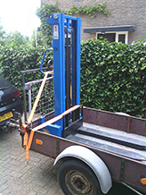 Vier robuuste spanbanden (op deze foto twee zichtbaar) worden gratis meegeleverd en moeten gebruikt worden. Onze aanhanger -die te huur is- heeft een lage tildrempel, en een hoog rek voor het vastzetten. 